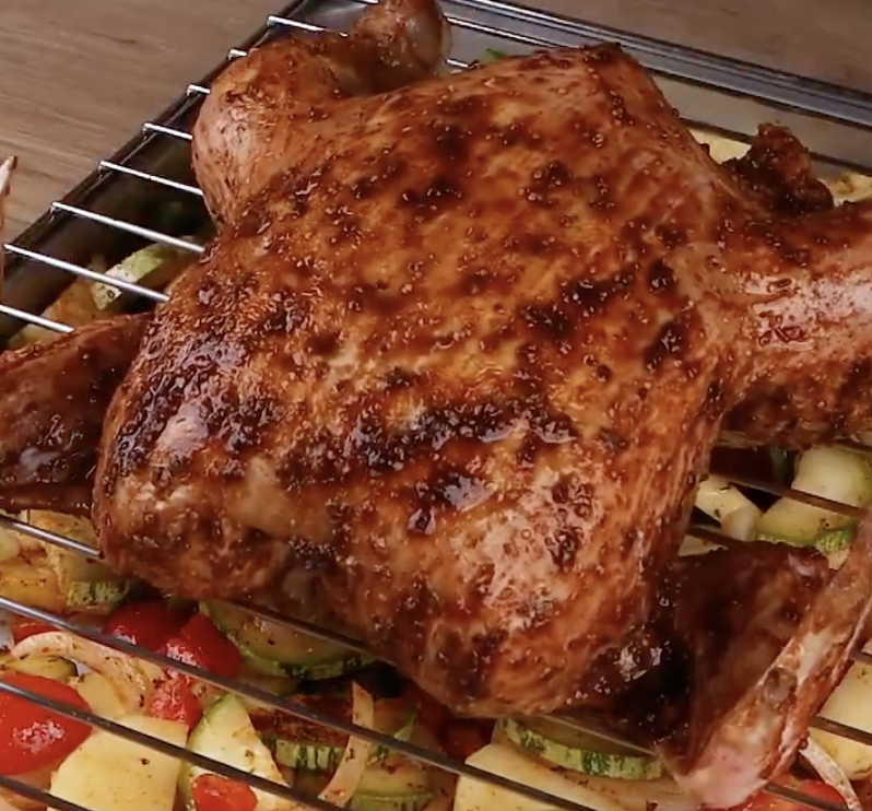 Whole chicken on a rack over veggetables 